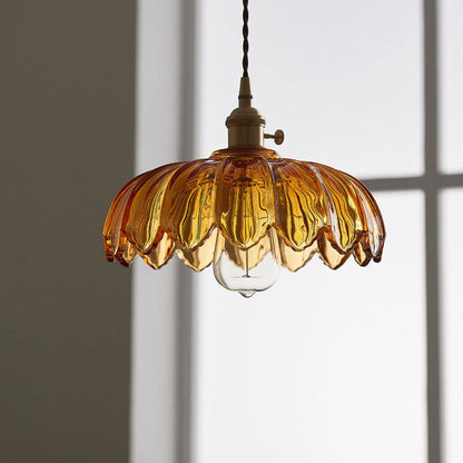  Een stijlvolle hanglamp met een amberkleurige glazen kap met golvende randen, die een warme gloed verspreidt. De lamp is bevestigd aan een gouden fitting met een gedraaide kabel, waardoor een vintage uitstraling ontstaat. De lichtbron is zichtbaar en geeft een uitnodigende sfeer aan de ruimte, terwijl de subtiele achtergrond de elegantie van de lamp benadrukt.